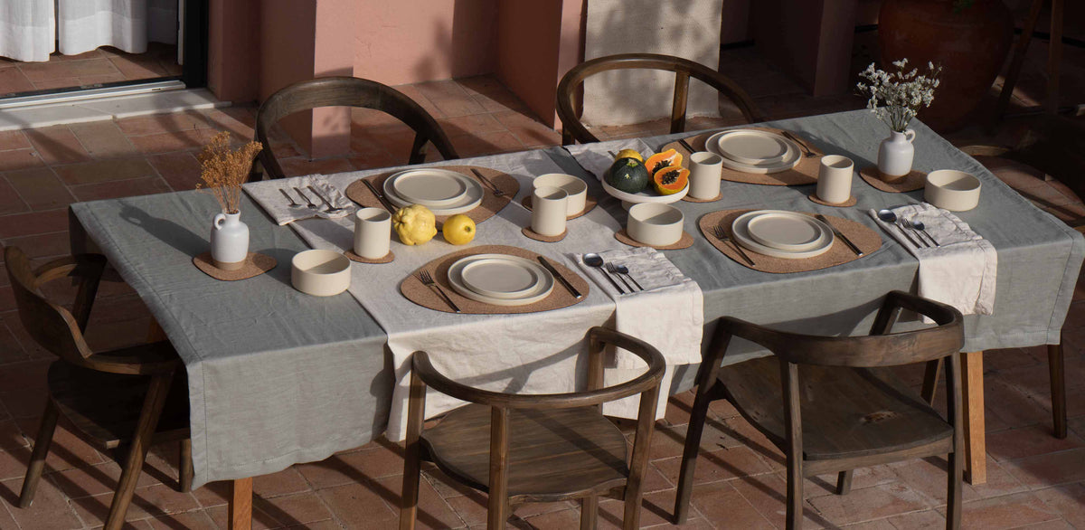 Ein für das Mittagessen gedeckter Tisch im Freien mit „ Far & Away  “Steinzeug, Besteck und Tischsets aus Kork