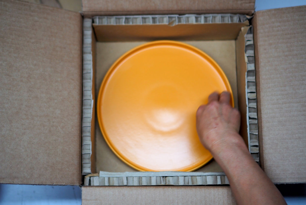 Ein Teller wird in einen recycelbaren Karton verpackt