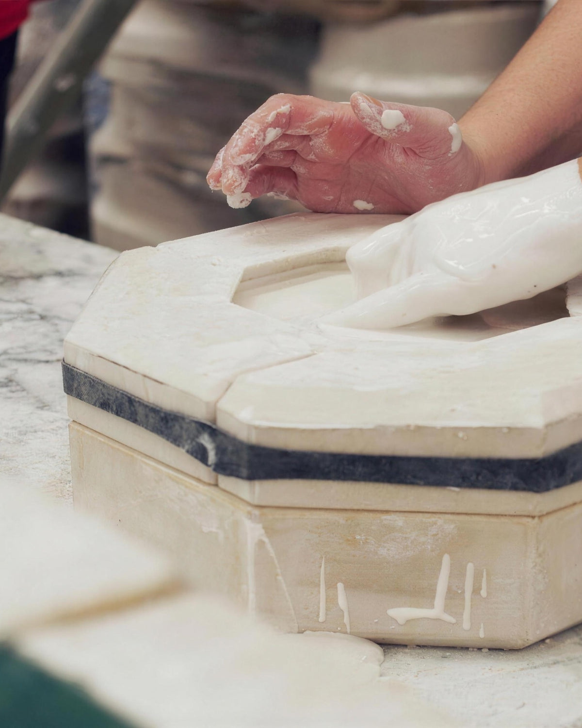 A maker smoothing clay in a plaster mould